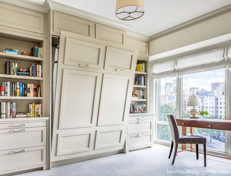 a dining room table and chairs with built in bookshelves next to the window