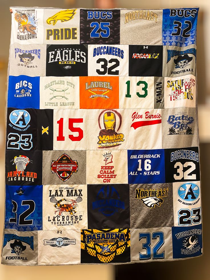 a man holding up a large quilt with many different patches on it