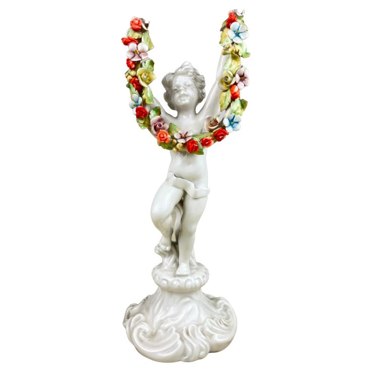 a white statue with flowers around it's neck and hands in the shape of a woman