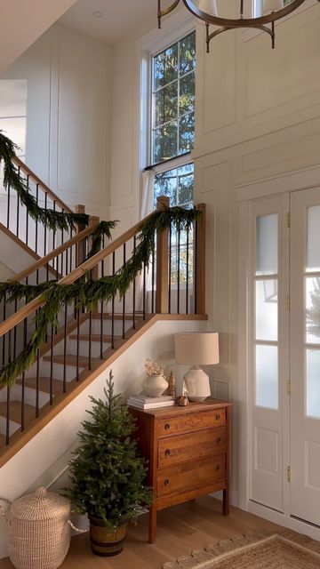 there is a christmas tree next to the stairs in this house with white walls and wood flooring