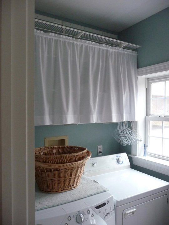 a laundry room with washer and dryer next to a basket on the window sill