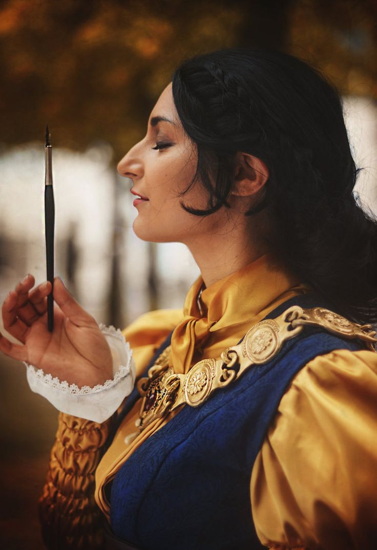 a woman dressed as snow white holding an object in her hand and looking at it