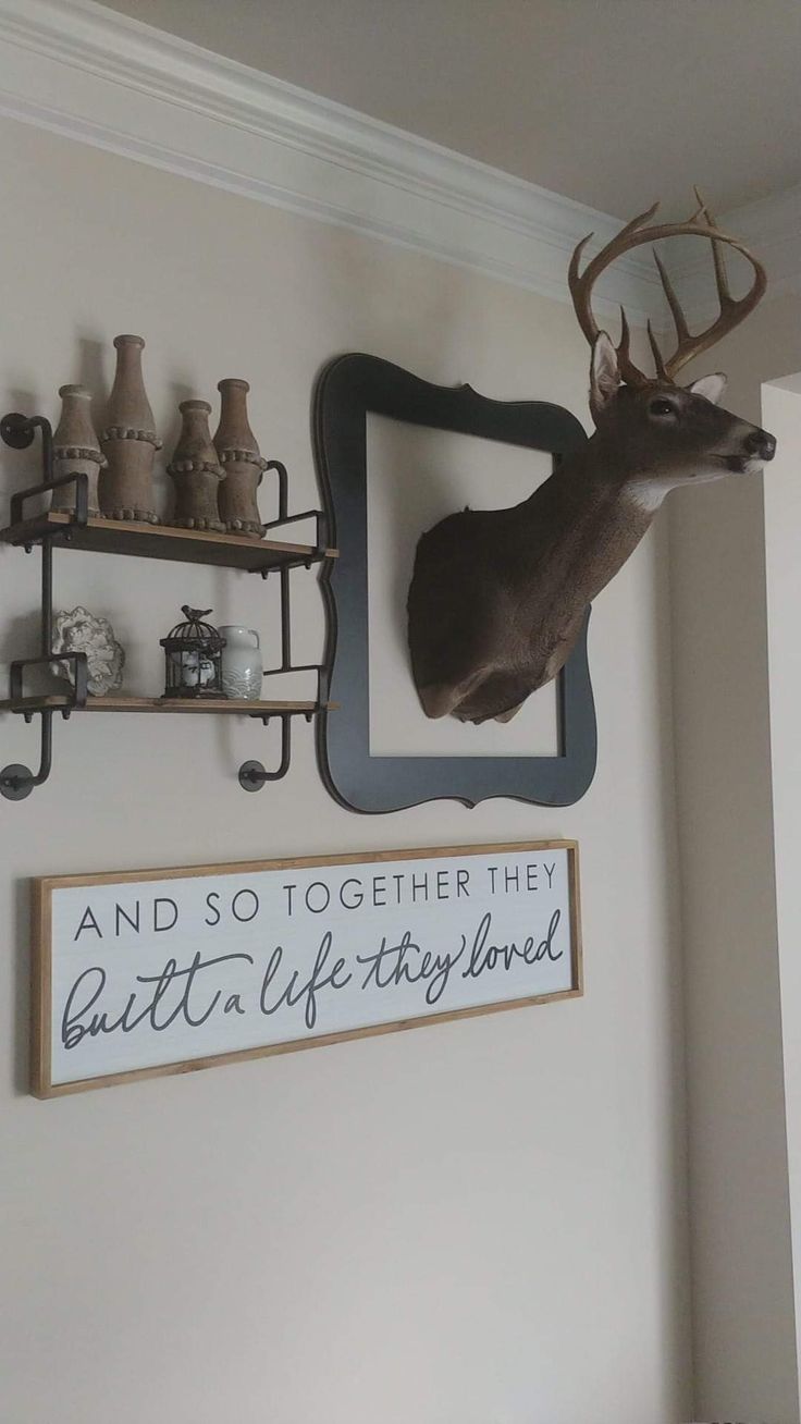 there is a deer head mounted on the wall next to shelves with vases and jars