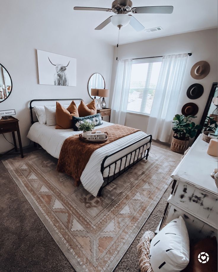 a bed room with a neatly made bed next to a window and a ceiling fan