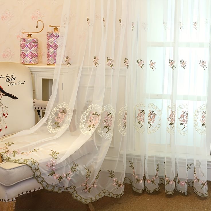 a white chair sitting in front of a window next to a wall with flowers on it