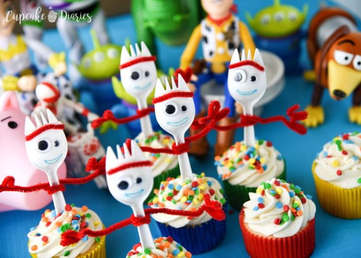 cupcakes decorated with cartoon characters and sprinkles on a blue table