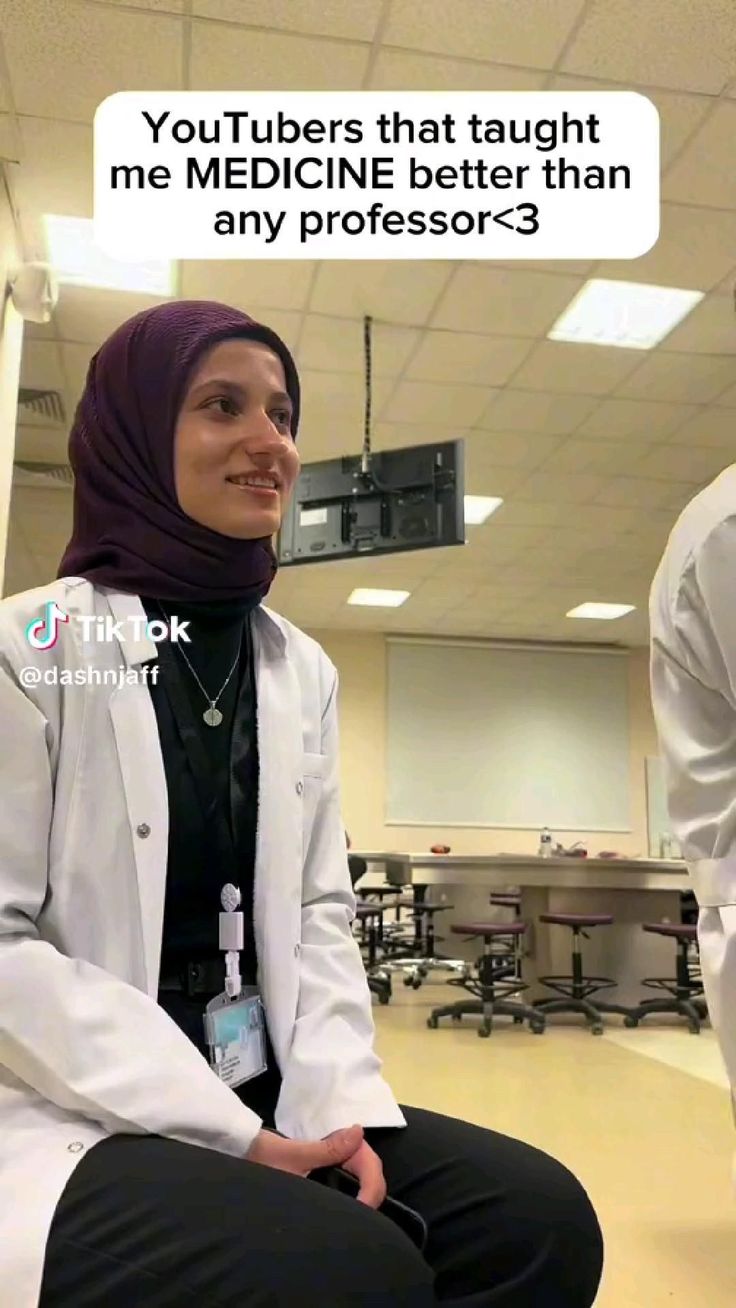 a woman in a white lab coat sitting on top of a chair next to another person