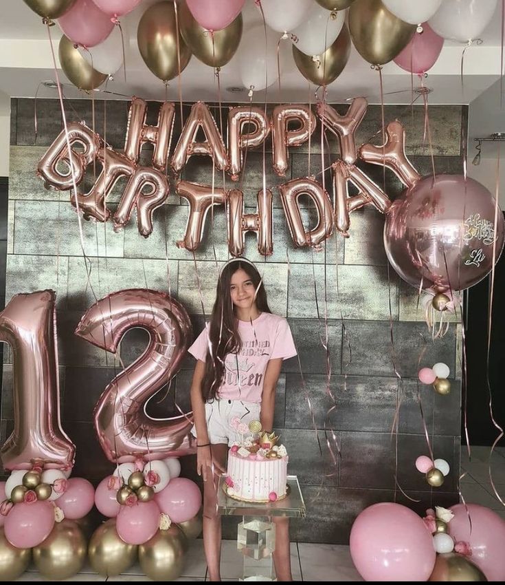 a girl standing in front of a happy birthday sign with balloons and streamers around her