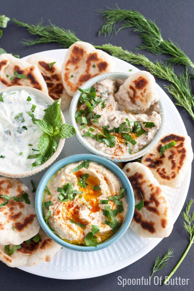 an assortment of pita breads and dips on a plate with parsley