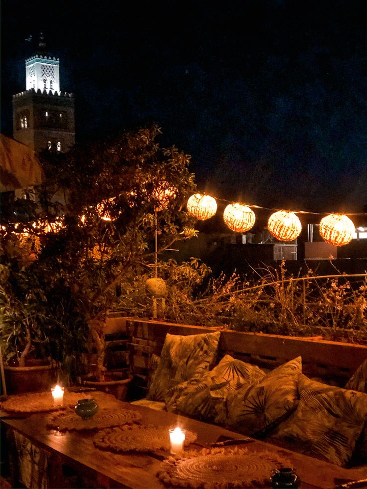 an outdoor seating area is lit up with candles