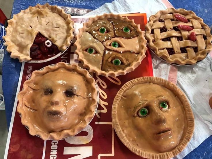 four pies with faces painted on them sitting on a table next to each other