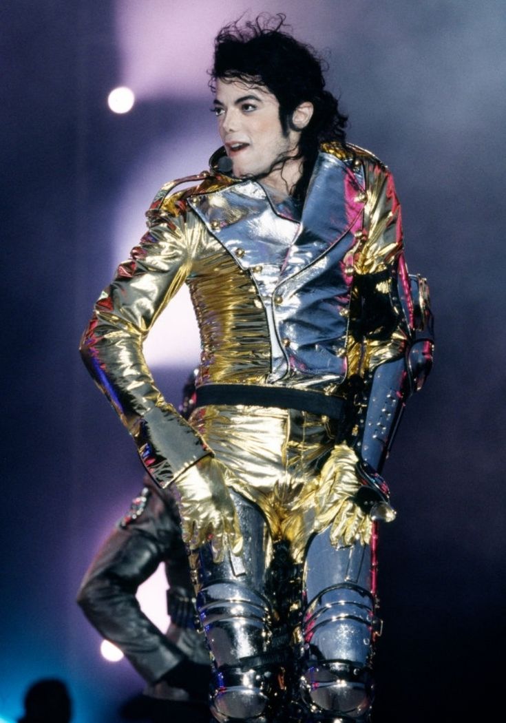 michael jackson on stage in gold and black outfit with his hands behind his back legs