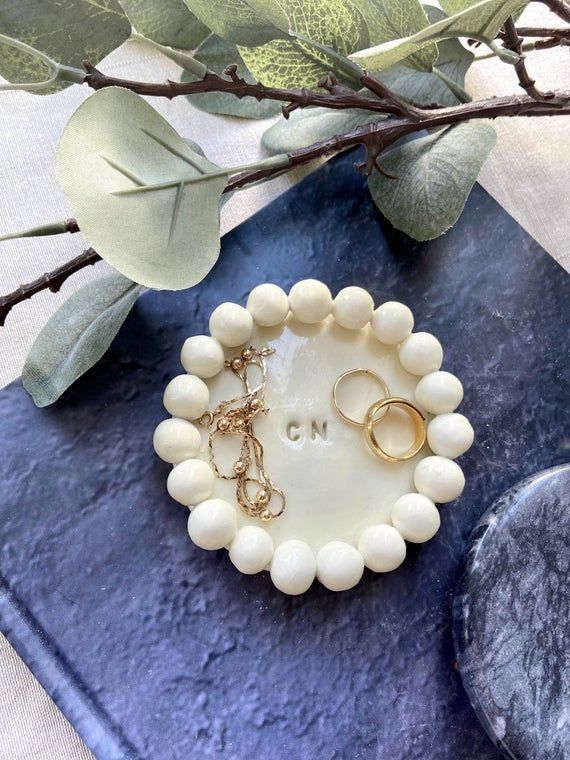 two white beaded bracelets sitting on top of a blue book next to a plant