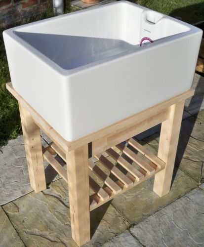 a large white sink sitting on top of a wooden stand next to a brick wall