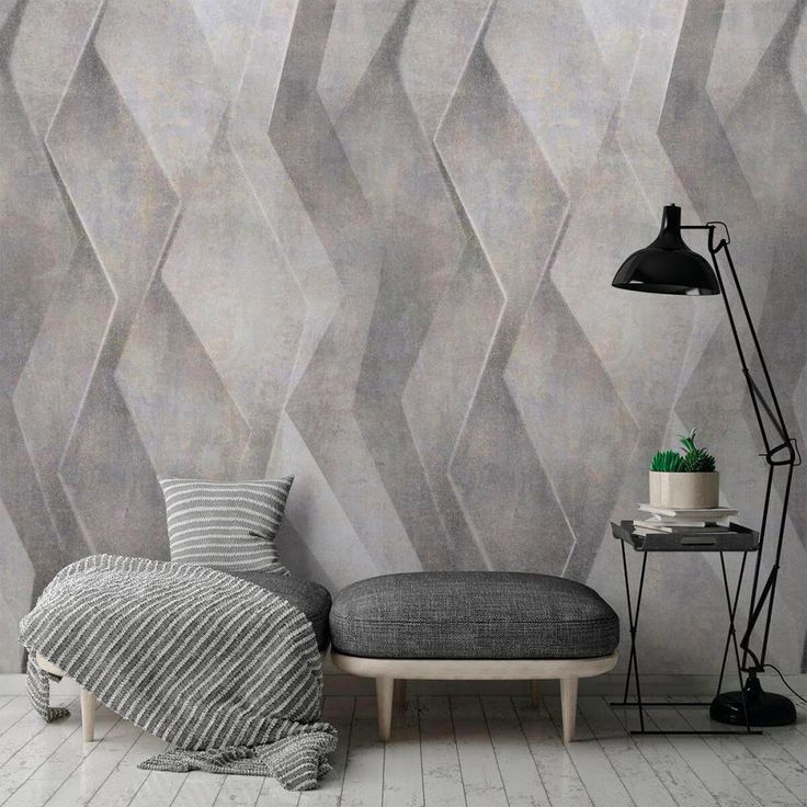 a room with a bed, lamp and wallpaper on the walls in grey tones