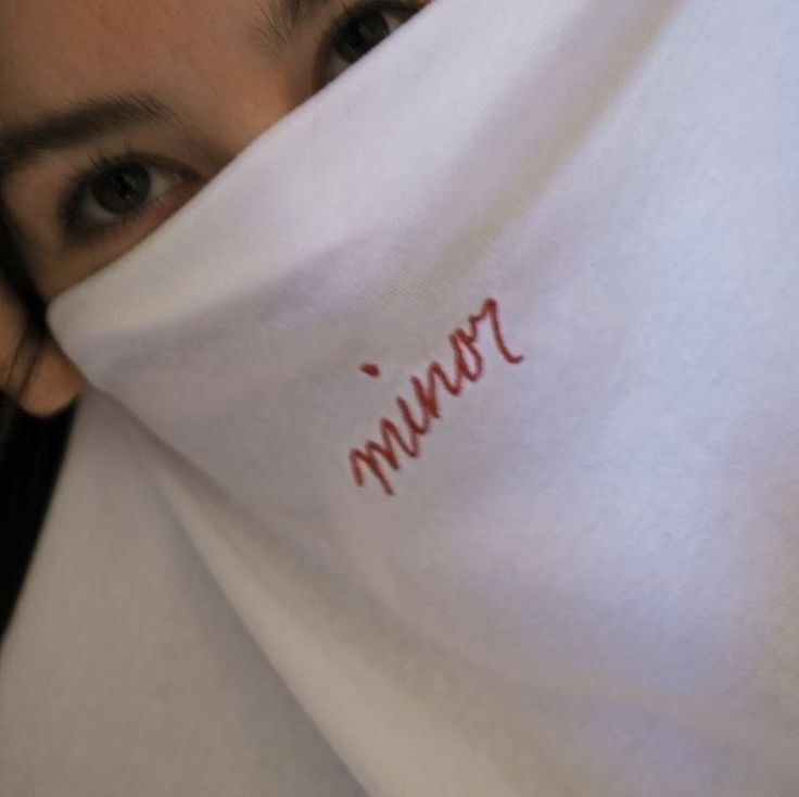 a close up of a person covering their face with a white shirt that says mmmm