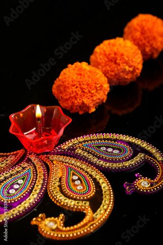 an intricately decorated diya with three pom poms next to it on a black surface