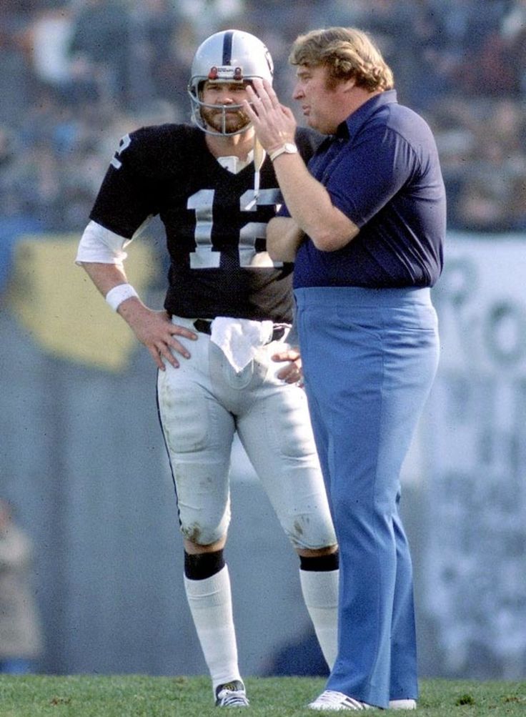 two football players are standing on the field and one is holding his hand to his face