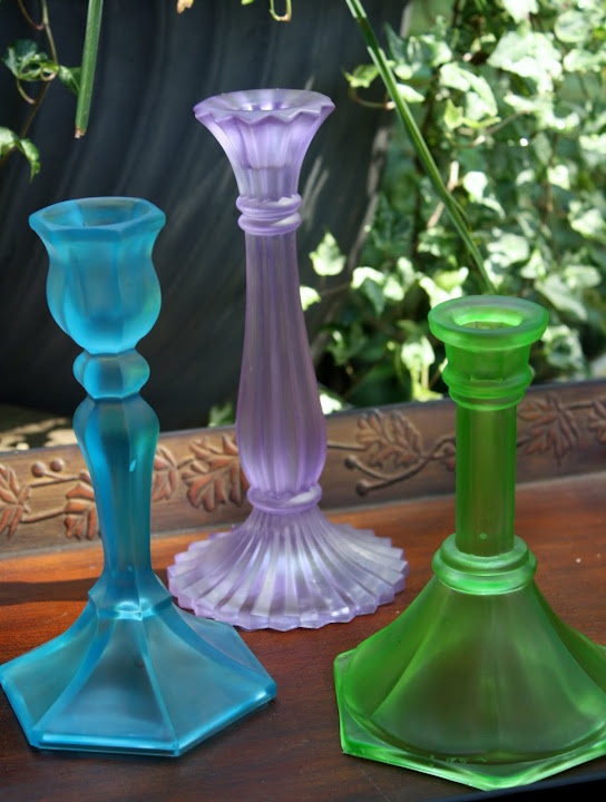 three different colored glass vases sitting next to each other on top of a table