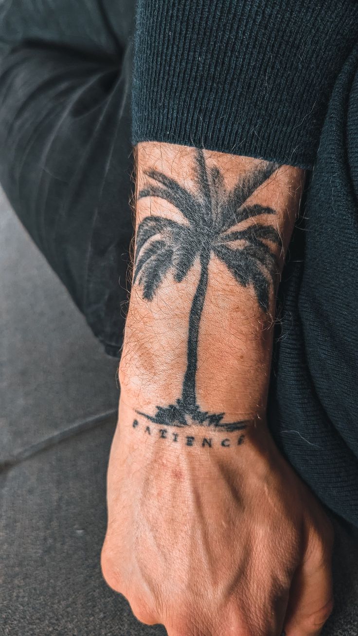 a man's arm with a palm tree tattoo on his left wrist and the word,