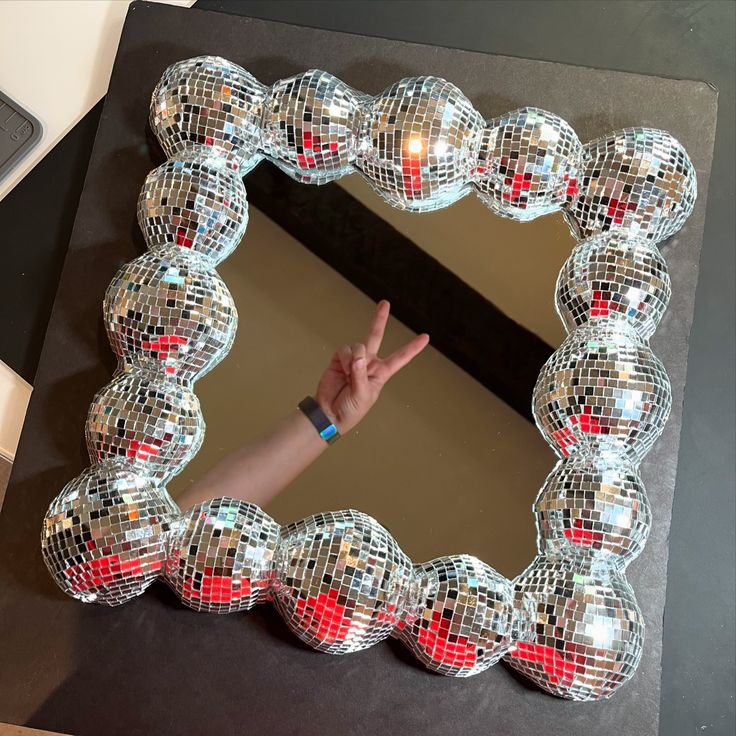 a mirror that has some disco balls in the shape of a frame on top of it