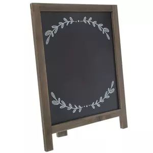 a chalkboard with a wreath drawn on the front and bottom, sitting against a white background