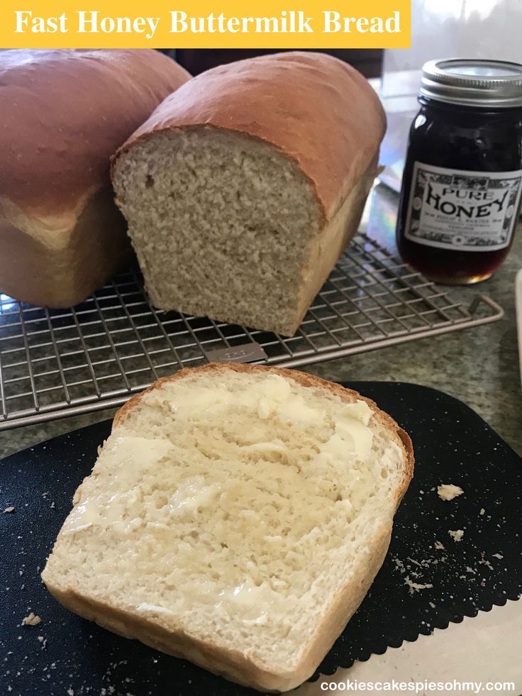 a loaf of bread sitting on top of a cooling rack next to a jar of honey