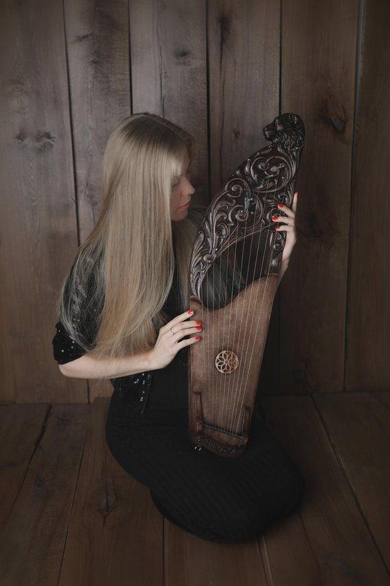 a woman sitting on the floor holding a harp