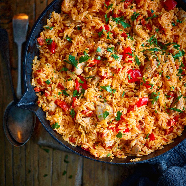 a skillet filled with rice and vegetables on top of a wooden table