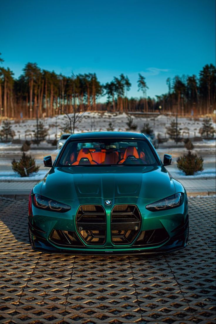 a green sports car parked in front of some trees