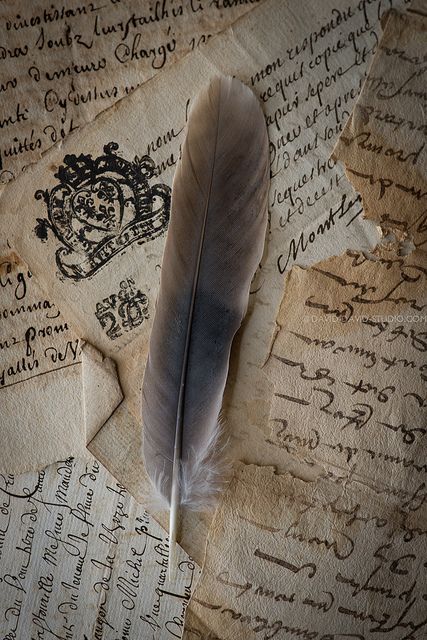 an old paper with writing and a feather resting on it's side next to a pen