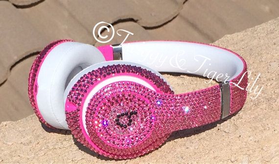 pink headphones with swarong on them sitting on a rock in the sun