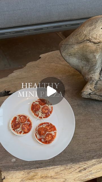 three mini pizzas on a white plate next to a frog statue and wooden bench