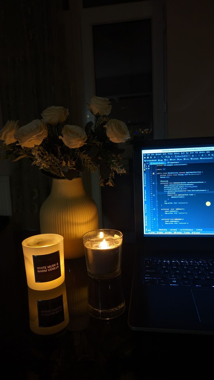 a laptop computer sitting on top of a table next to a candle