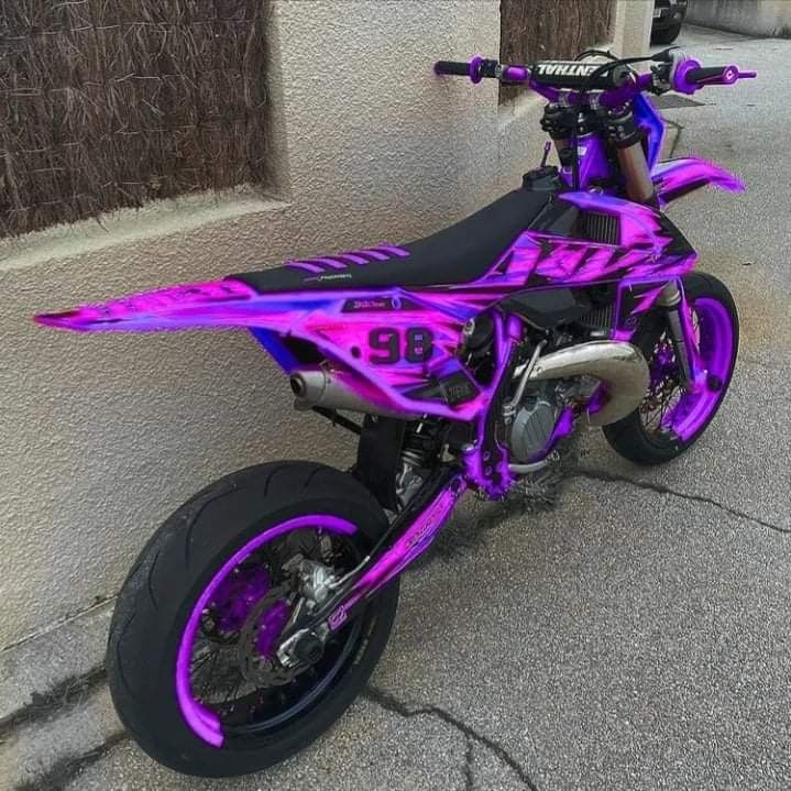 a pink dirt bike parked next to a building