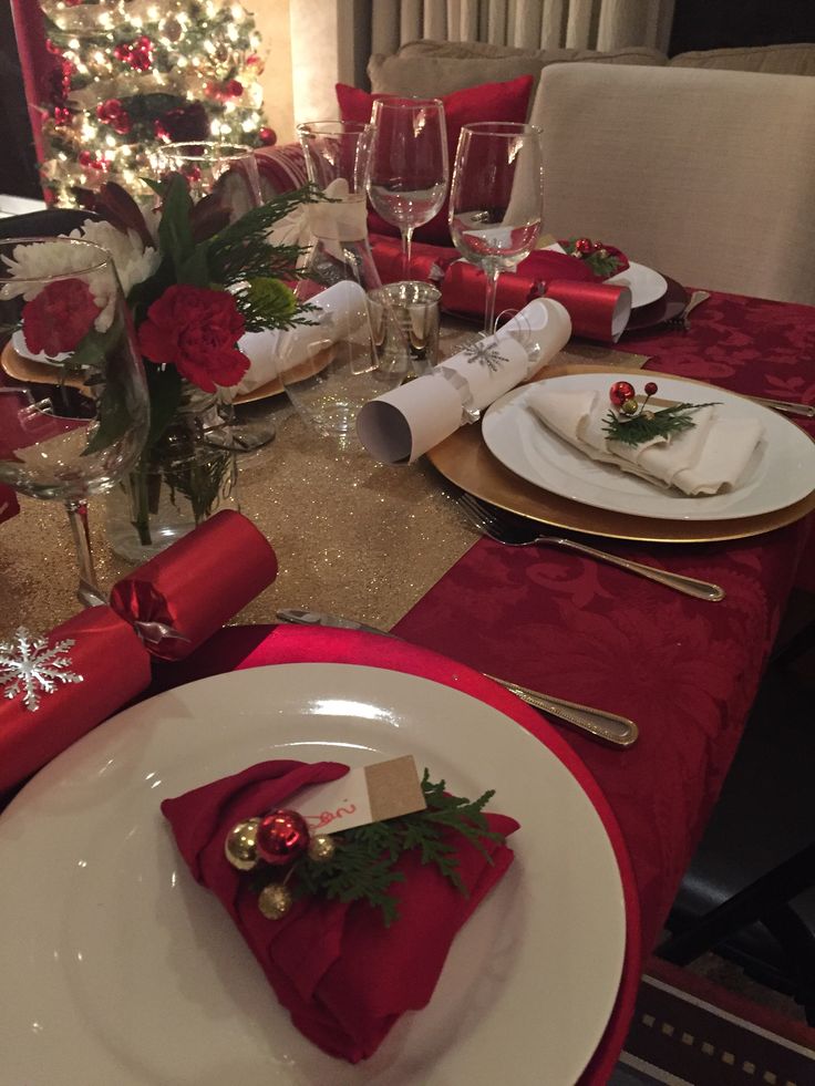 the table is set for christmas dinner with red napkins and place settings on it