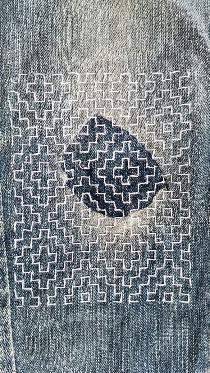 the back pocket of a pair of jeans with an embroidered pattern on it and a hole in the middle