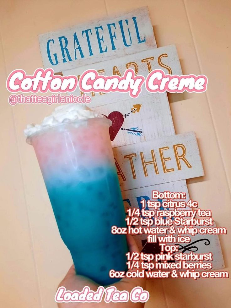 a blue and pink drink sitting on top of a table next to a wooden sign