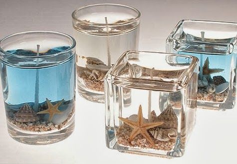 three clear glass vases filled with sand and starfish in them, one has a candle