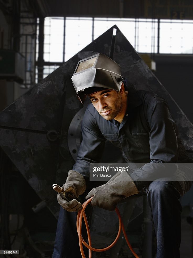 a man working on a piece of metal with a welding helmet and gloves stock photo