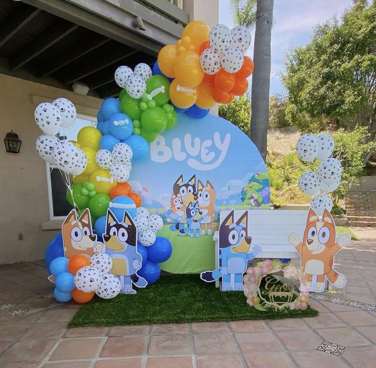 a bunch of balloons that are sitting on the ground in front of a sign and some grass