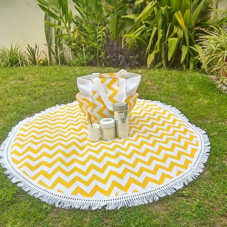 a yellow and white picnic blanket with mason jars on it in the middle of a yard