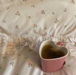 a heart shaped cup sitting on top of a bed