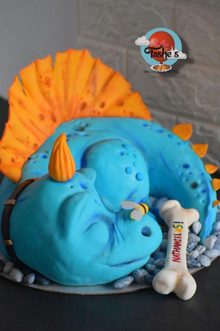 there is a cake that looks like a dinosaur sleeping on the ground with a bone in its mouth