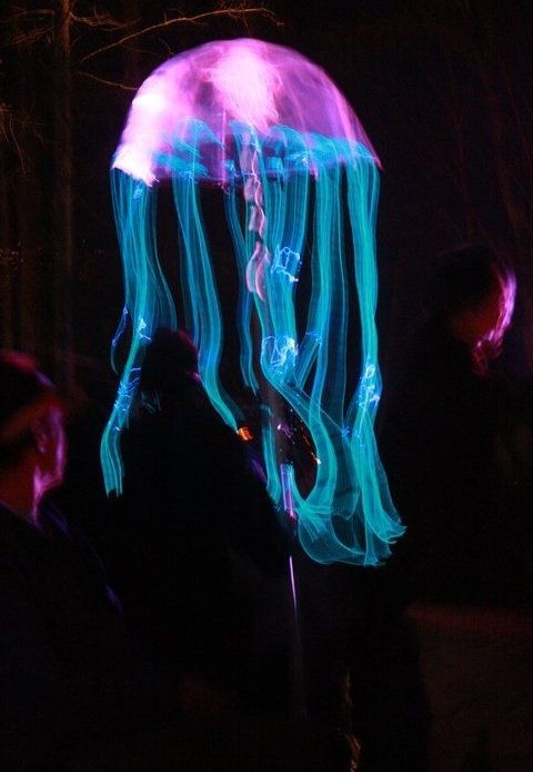 a group of people standing next to each other in front of a purple jellyfish