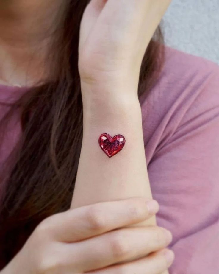 a woman wearing a red heart tattoo on her wrist