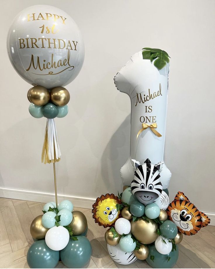 two balloons and some animals are on the floor next to each other in front of a birthday balloon