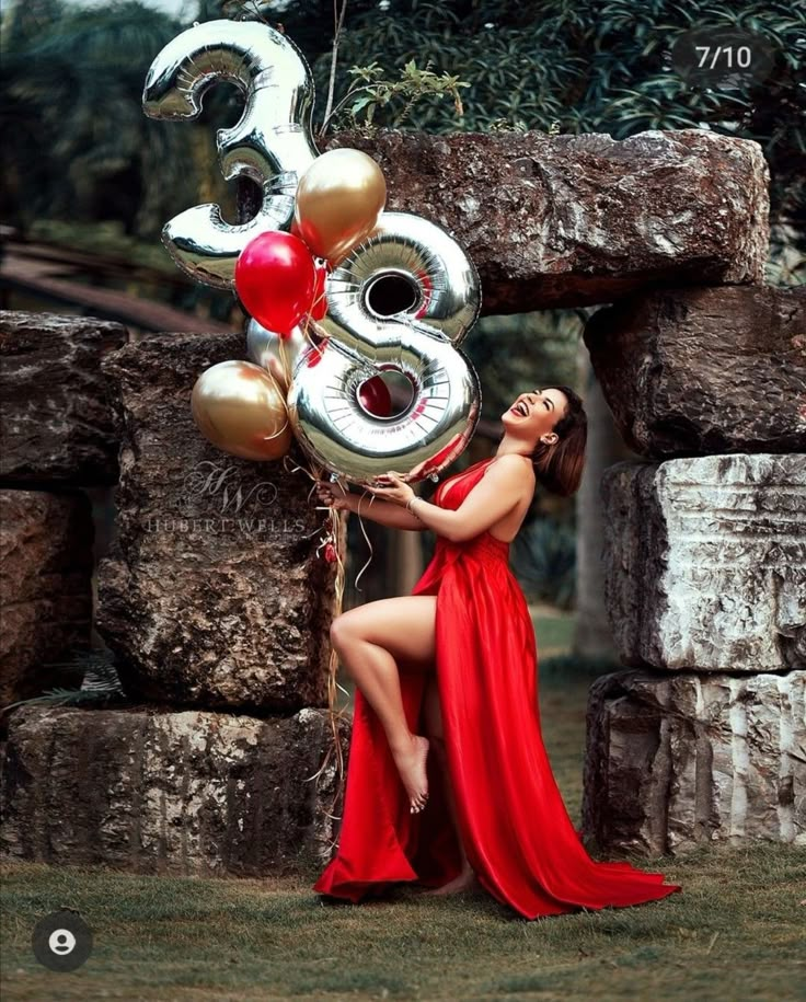 a woman in a red dress is holding some balloons and the number thirty three on it