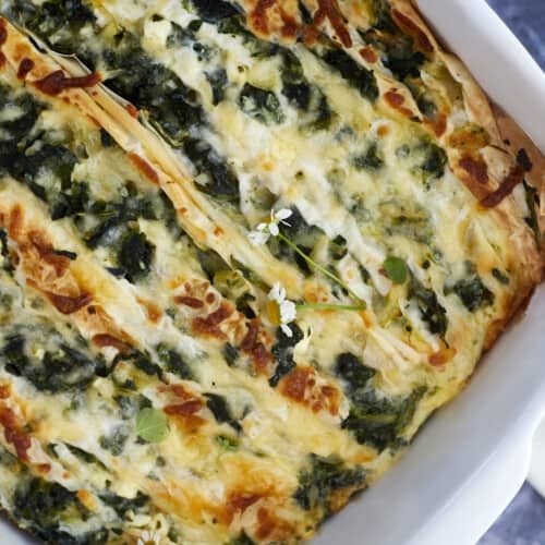 a casserole dish with spinach and cheese in it sitting on a table