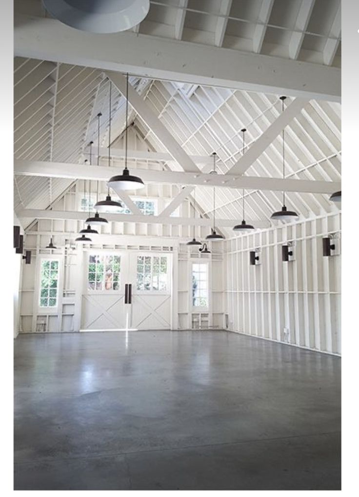 an empty room with several lights hanging from it's ceiling and windows above the floor